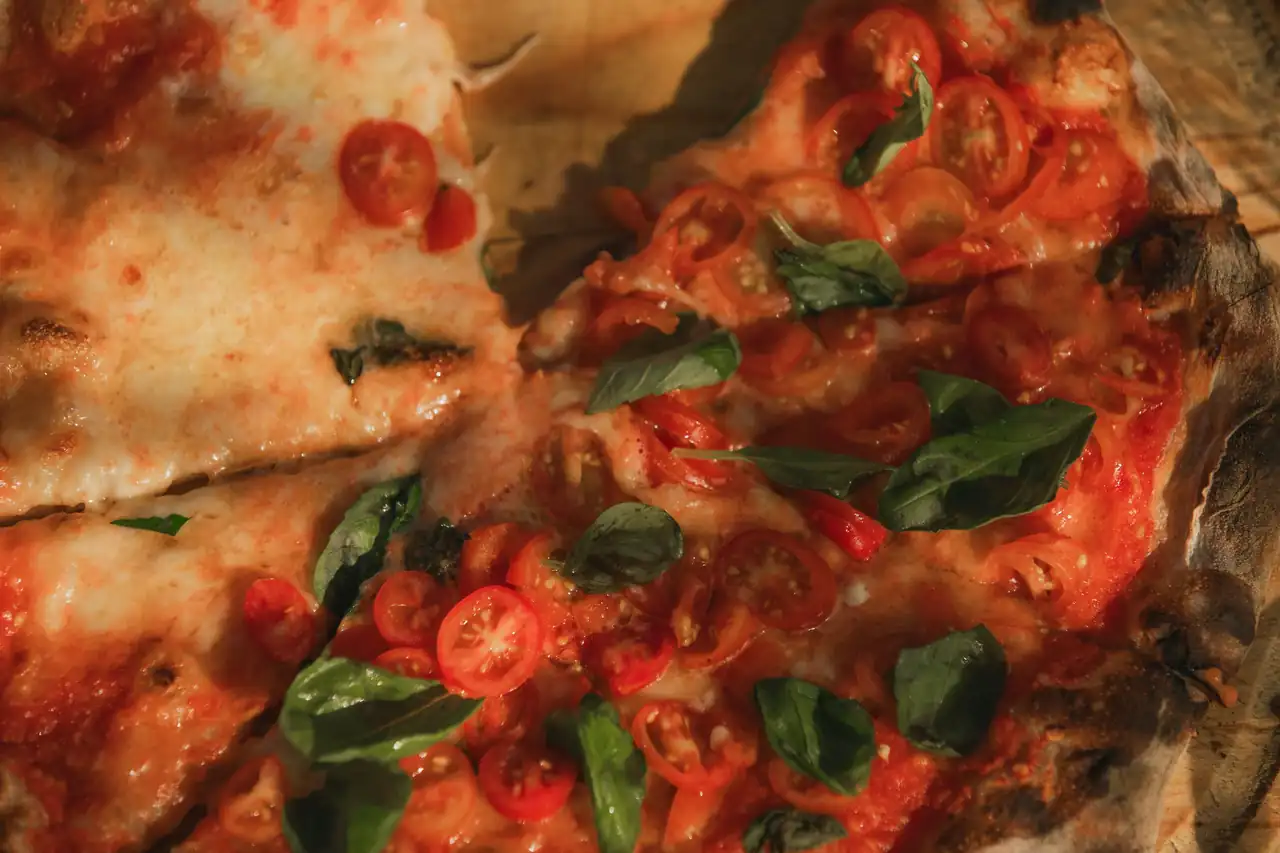 Wood-fired pizza topped with roasted Mediterranean vegetables and cherry tomatoes