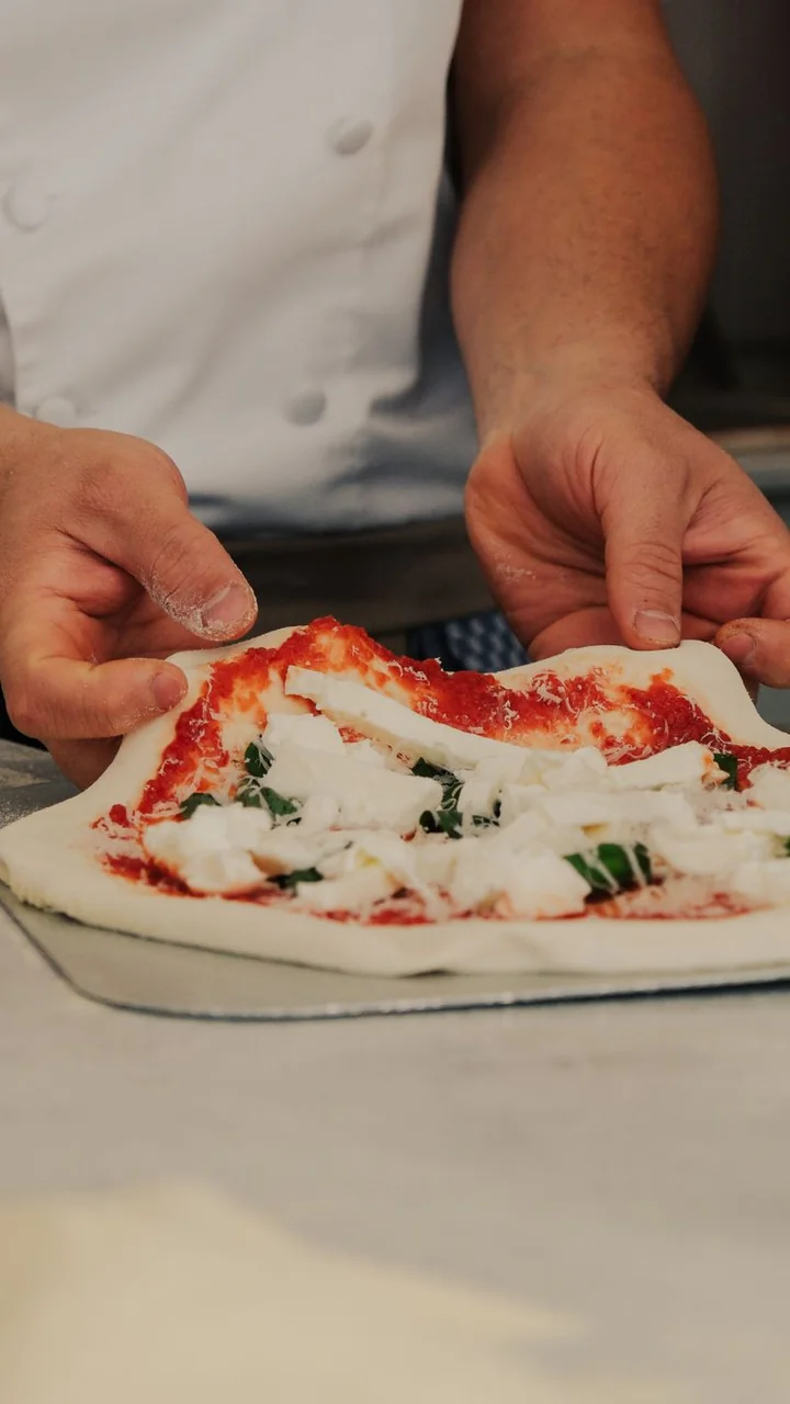 Vibrant fresh green basil leaves placed on prepared pizza