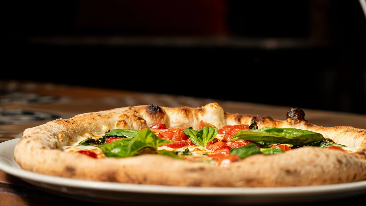 Vibrant fresh green basil leaves placed on baked pizza
