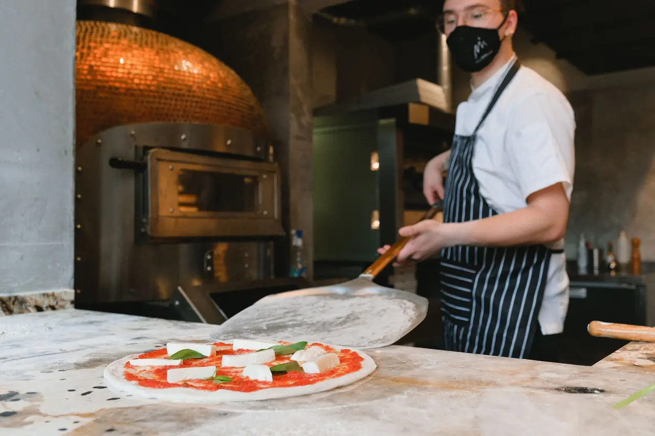 Artisan wood-fired pizza baking in a traditional stone oven at Koraven Thessique