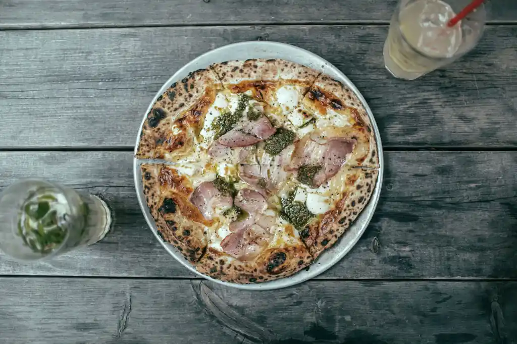 Wood-fired artisanal pizza on a rustic dining table at Koraven Thessique